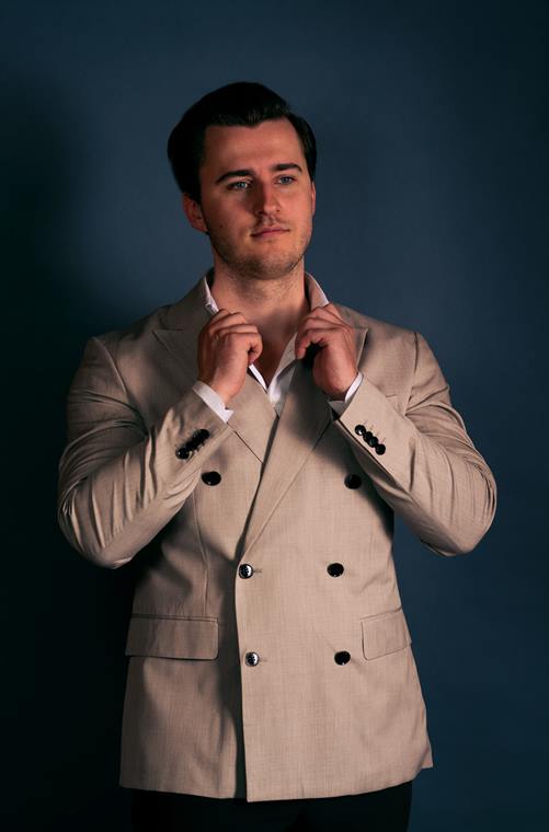 Mann im hellen Zweireiher richtet den Kragen, Business-Portrait