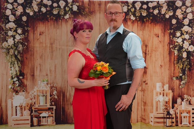 Paar vor einer Fotowand mit Blumen und Holz