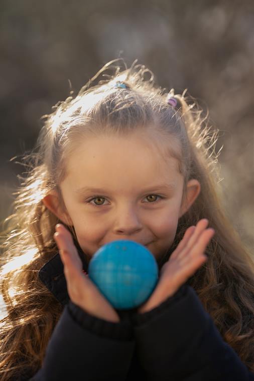 Mädchen hält einen blauen Ball an den Mund