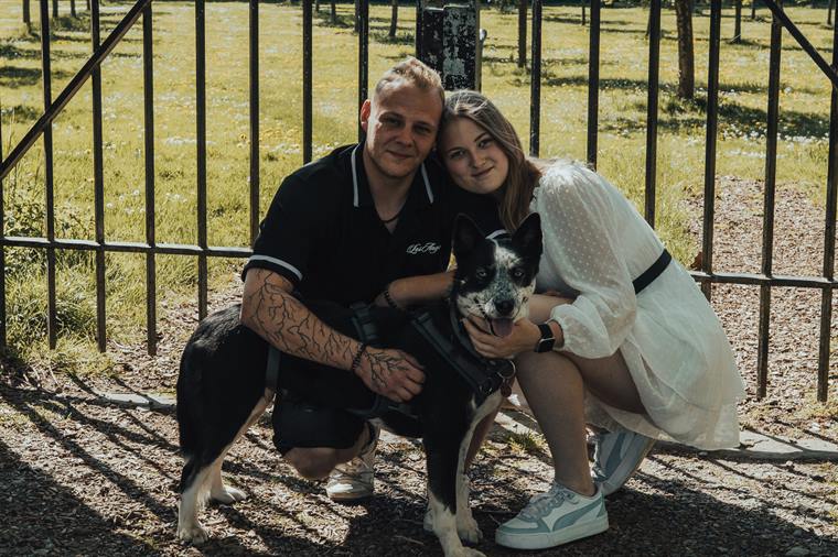 Paar mit Hund vor einem Zaun