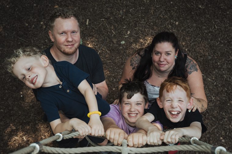 Familie mit drei lachenden Jungen am Kletternetz, von oben fotografiert