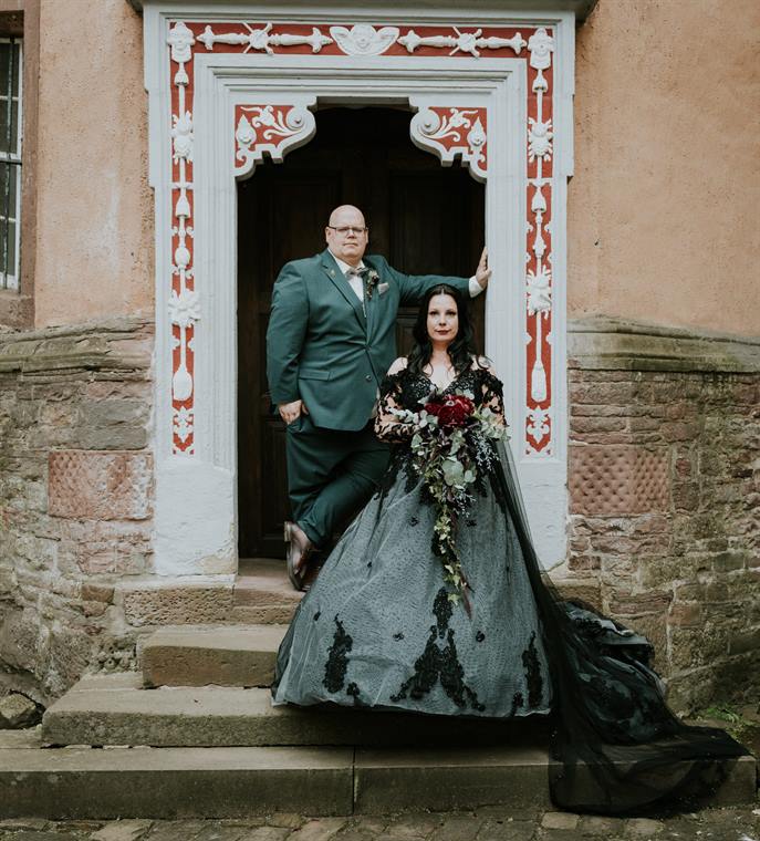 Brautpaar in einem verzierten historischen Portal, die Braut im dunklen Kleid