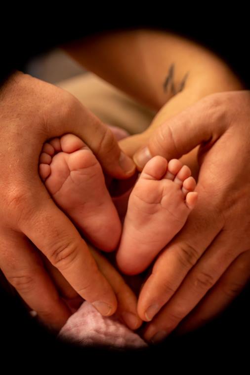 Babyfüße in den Händen der Eltern, zu einem Herz geformt