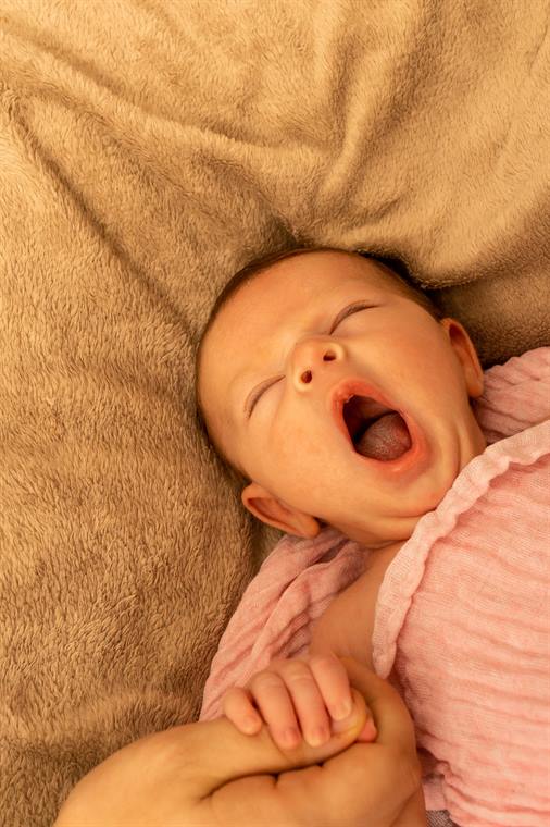 Neugeborenes gähnt auf einer weichen Decke