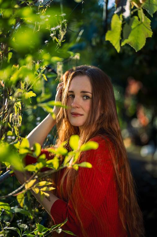 Frau mit langen Haaren zwischen Weinlaub