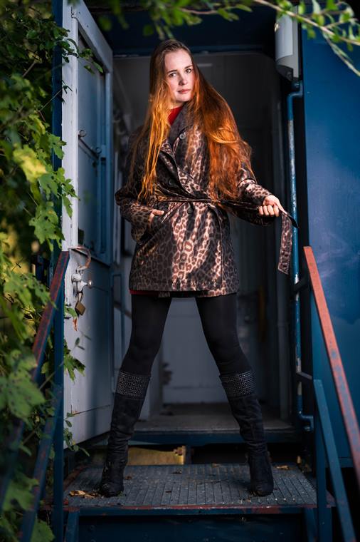 Frau im Mantel auf einer Metalltreppe