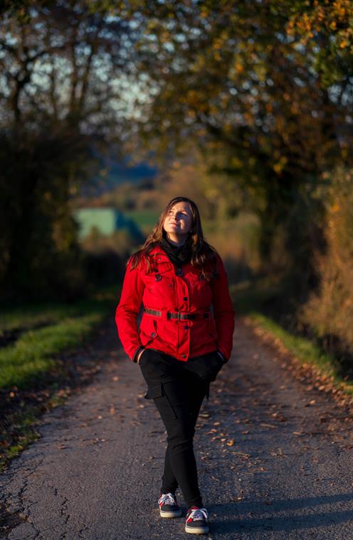 Frau in roter Jacke auf einem Feldweg