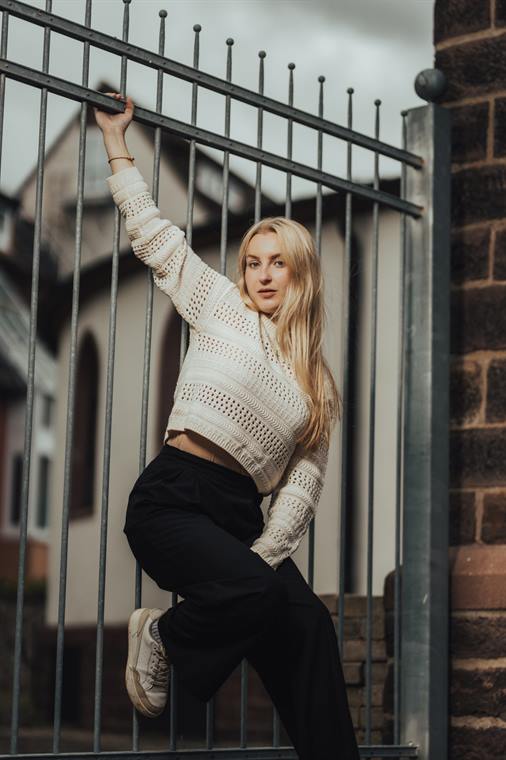 Blonde Frau klettert an einem Gartentor